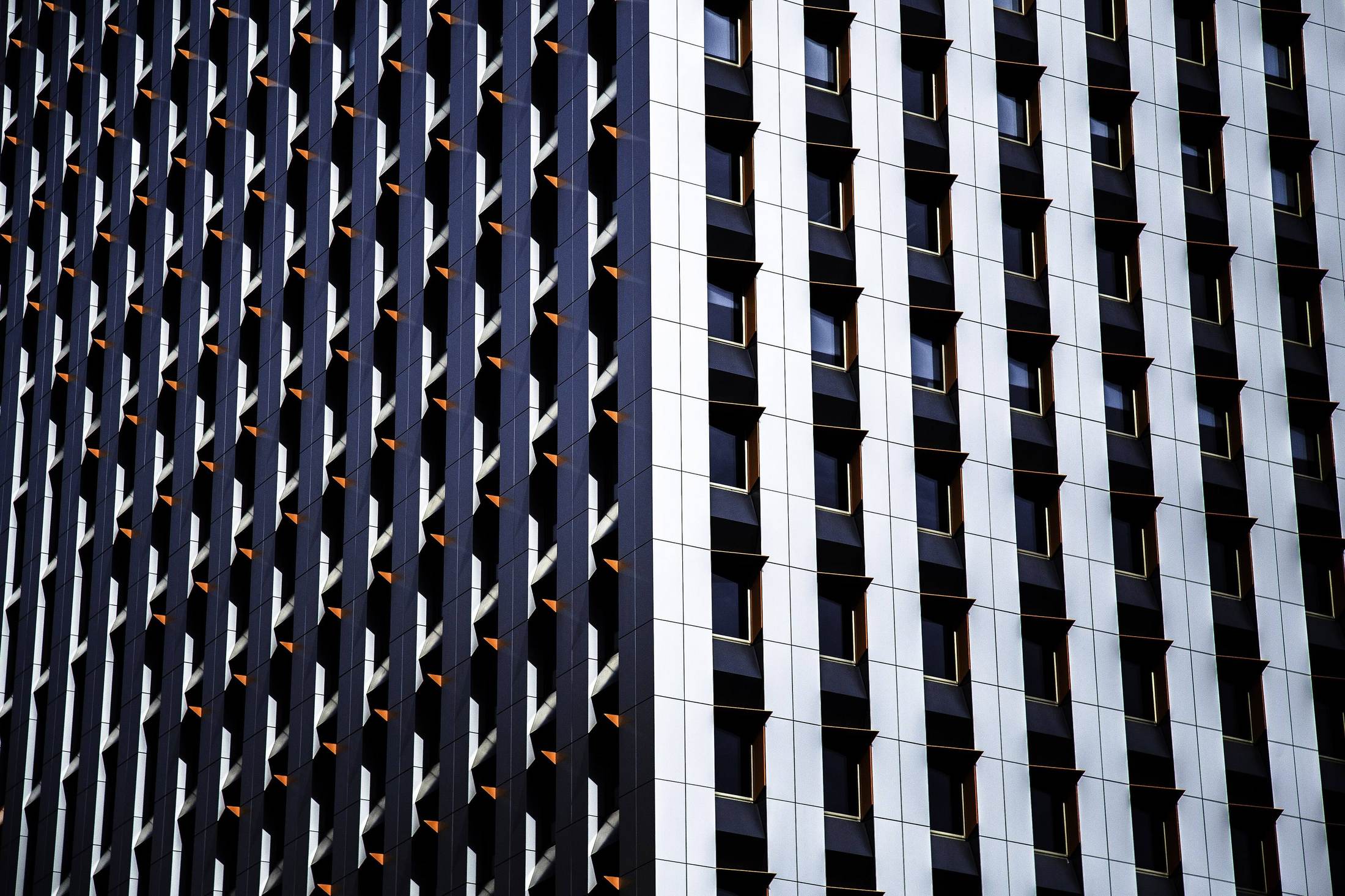 Hard-cropped study of a repeating curtain-wall facade, looking along two adjacent office towers.