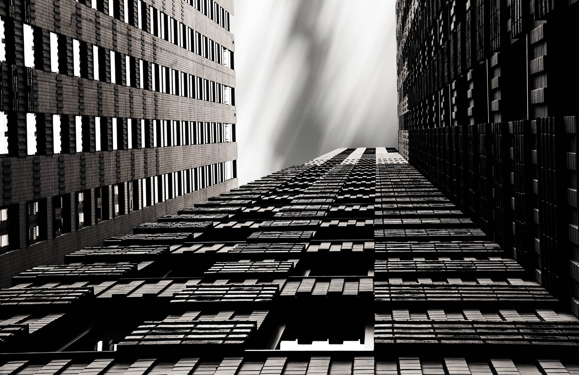 High-contrast monochrome study looking up the corner of a tall tower against an overcast sky.