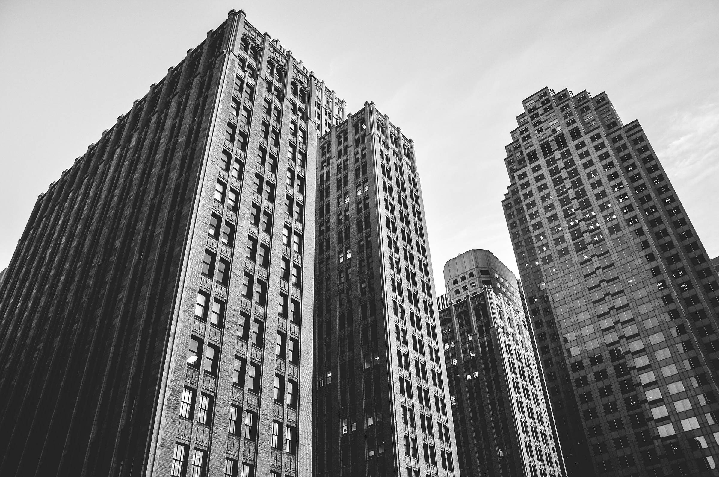 Tall office elevations stacked against each other, photographed upward in monochrome.