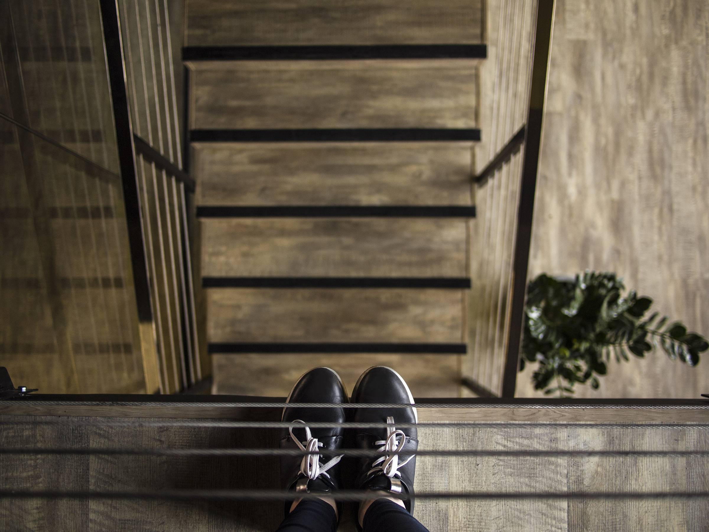 An overhead view of a person's feet at the top of a flight of steps, photographed in monochrome.