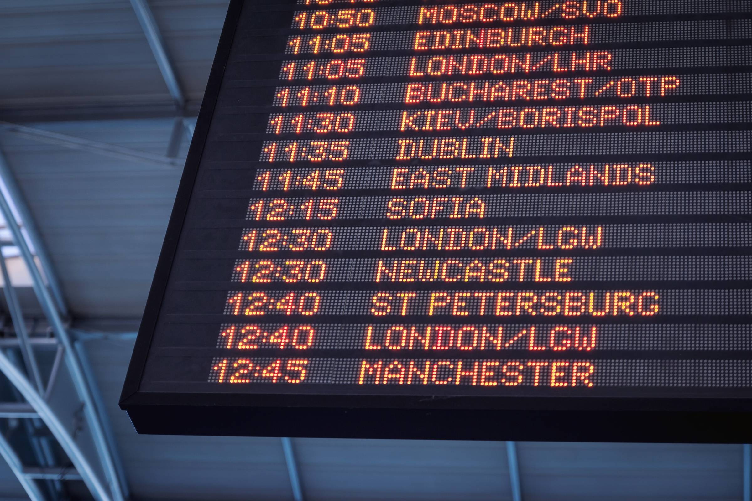 A mechanical split-flap departures board mid-flip, photographed in monochrome.