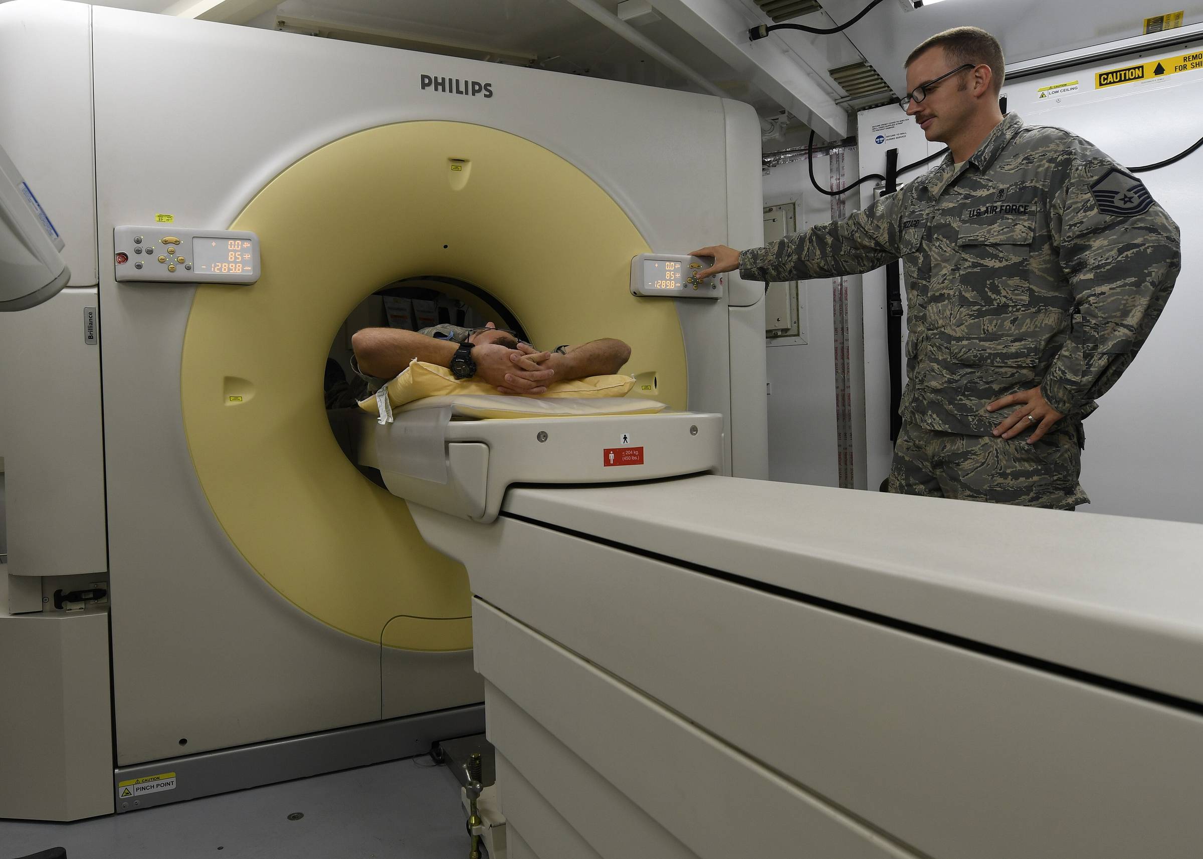 A computed-tomography scanner in a treatment room with its table extended.