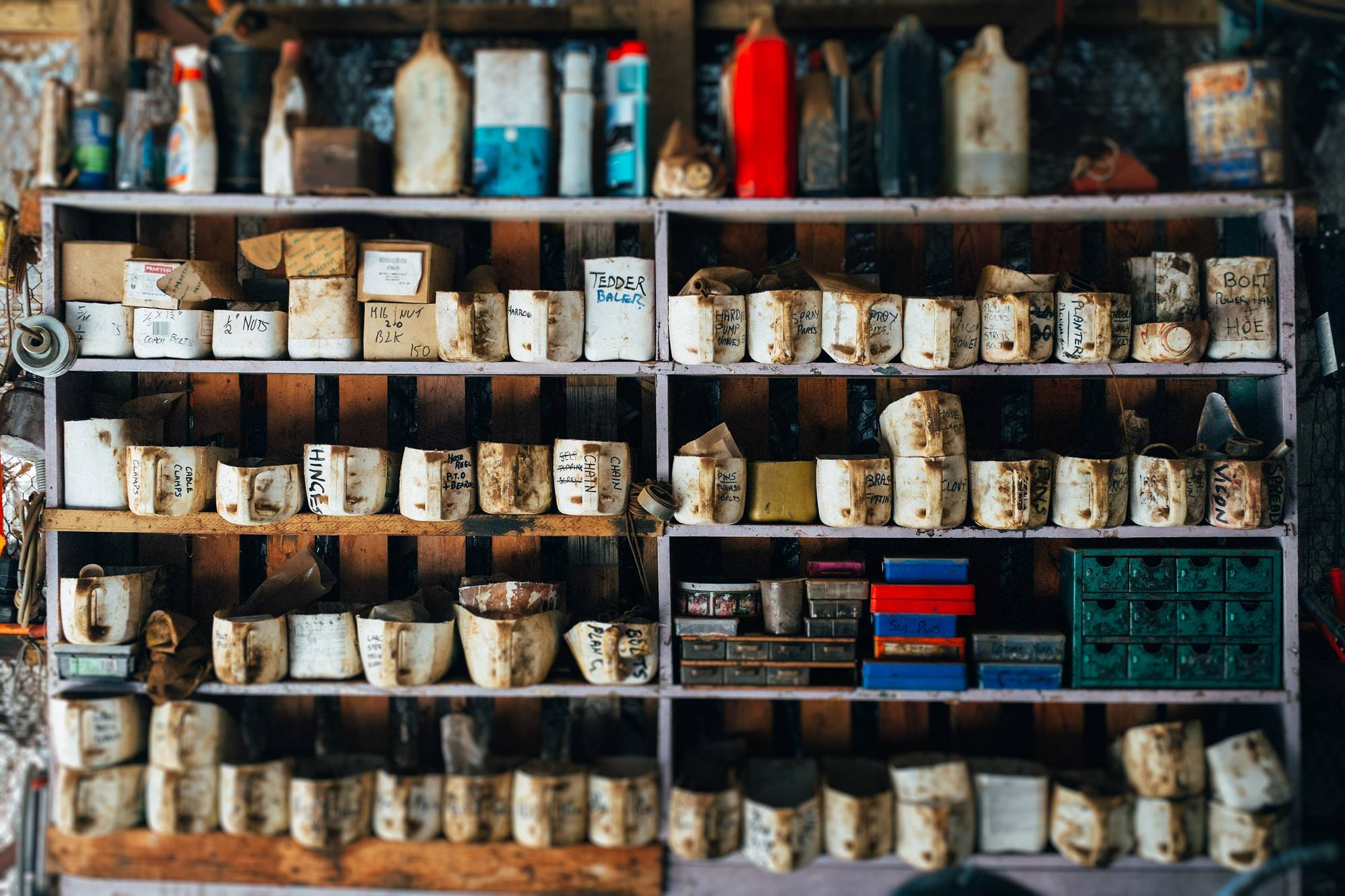 Shelves of jars and tins in a working stockroom, stacked three deep and sorted by size.