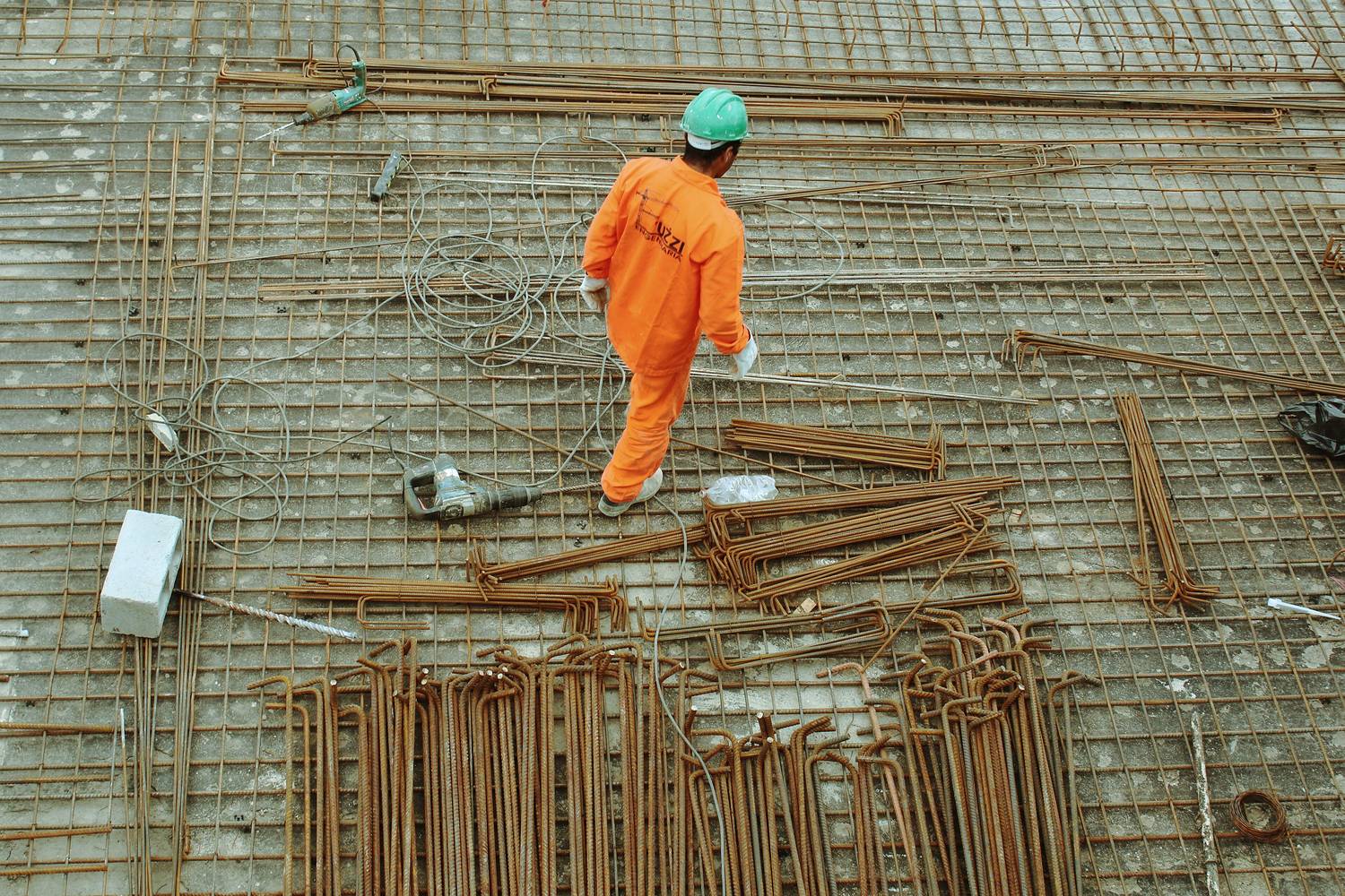 A worker standing on a raft of tied reinforcing steel at a construction site.