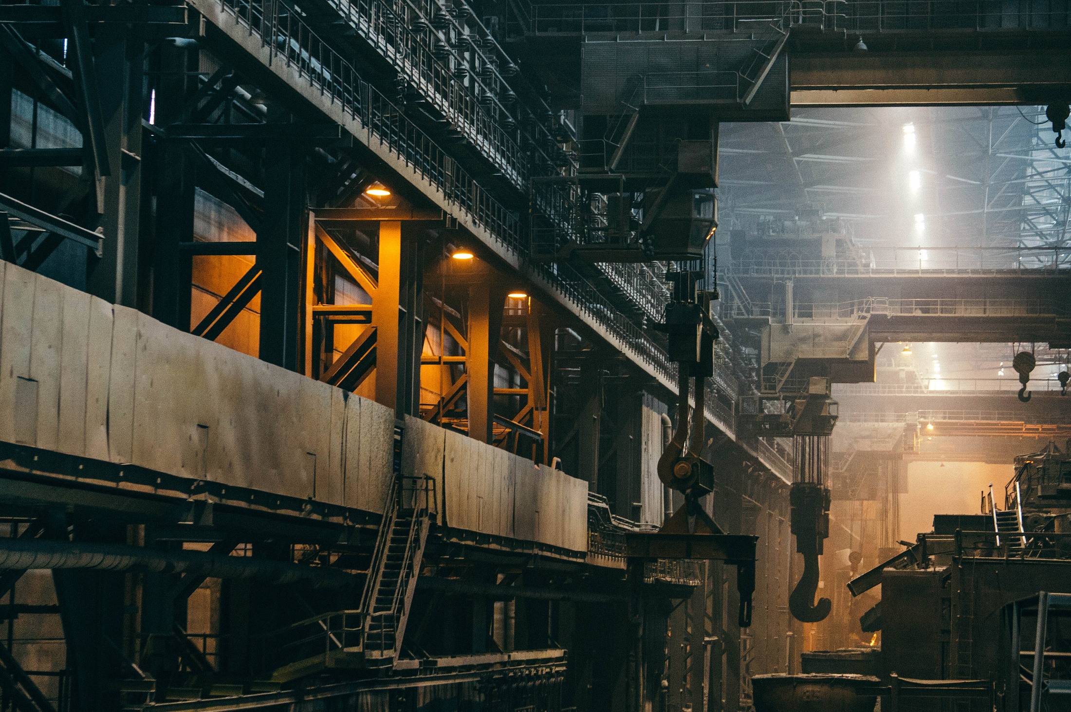 Gantry and conveyor structure inside a heavy industrial plant, seen from below against daylight.